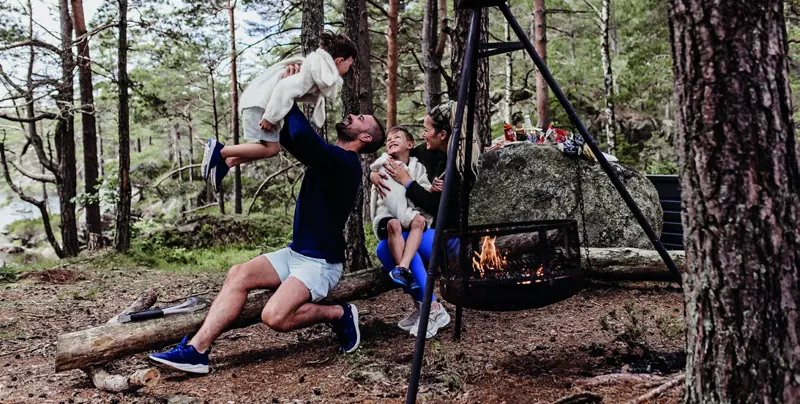 Familie griller ved bålpanne i skogen